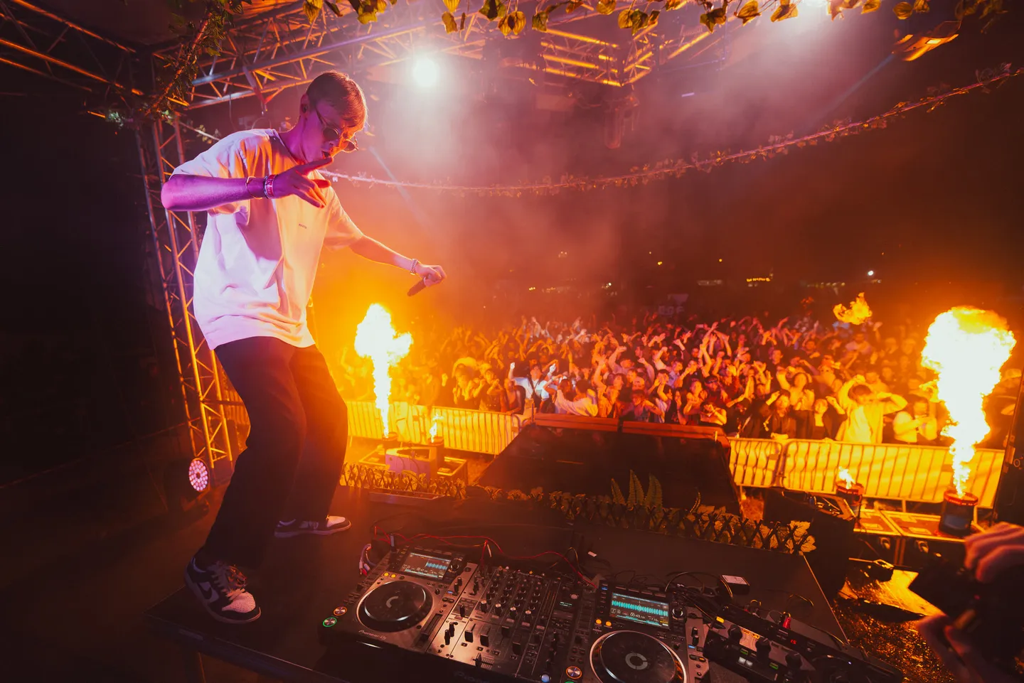 DJ sur scène face au public, entre jeux de lumière et jets de flammes
