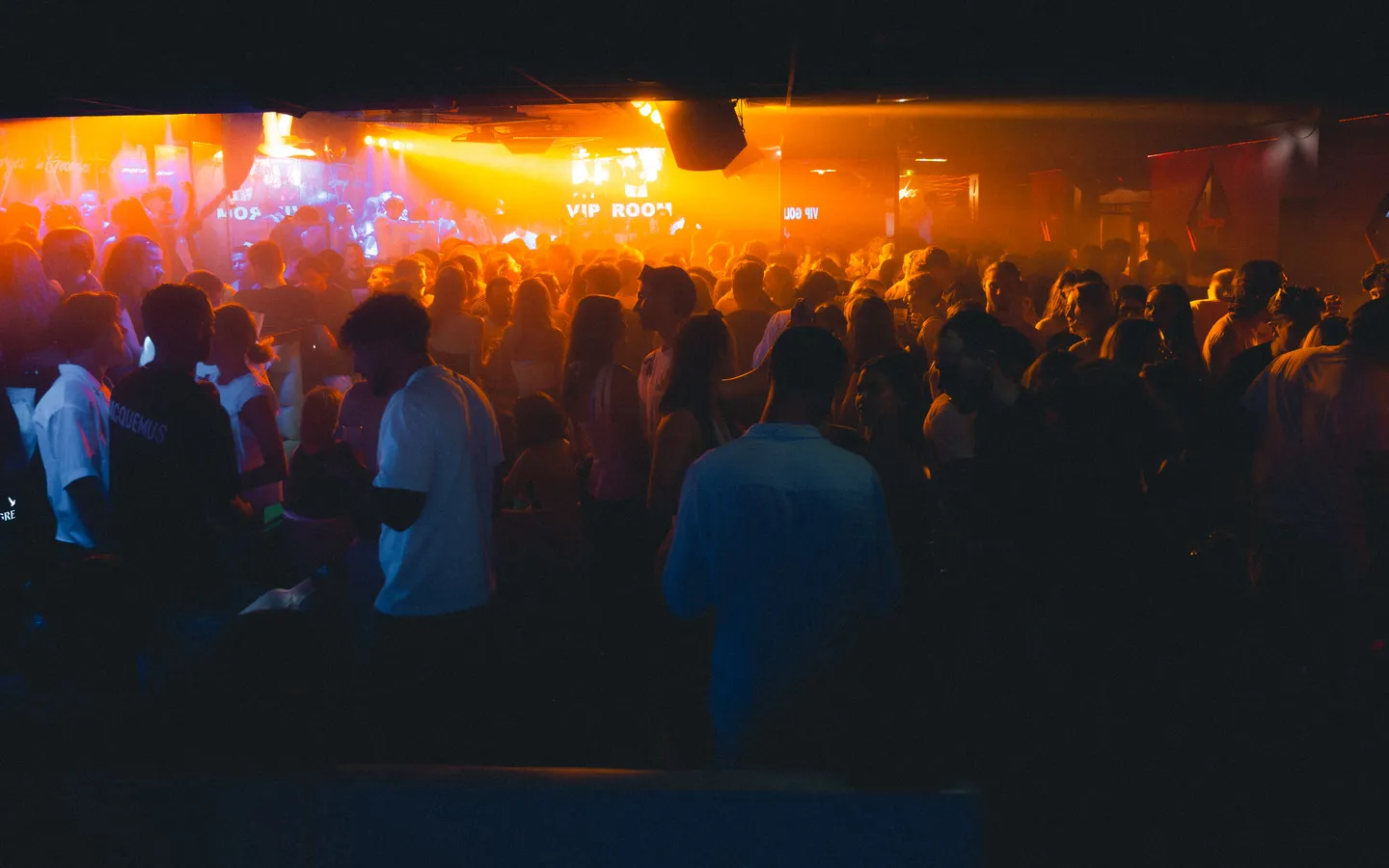 Public d’une discothèque sous les lumières orange de la scène