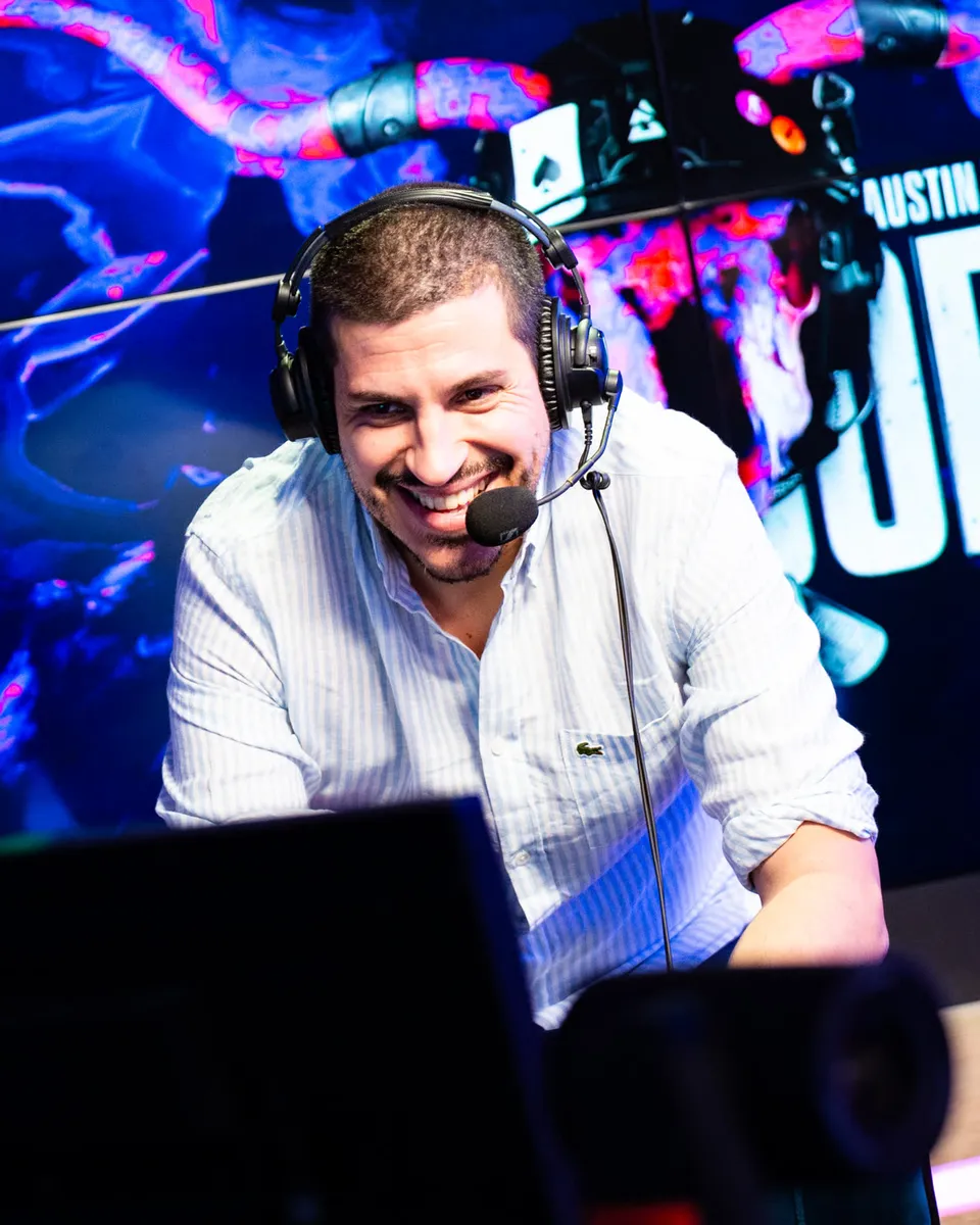 Commentateur au micro derrière un bureau sous des éclairages bleus