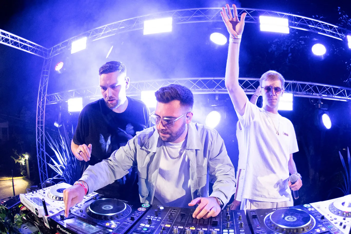 Trois DJ réunis derrière les platines sous les lumières bleues