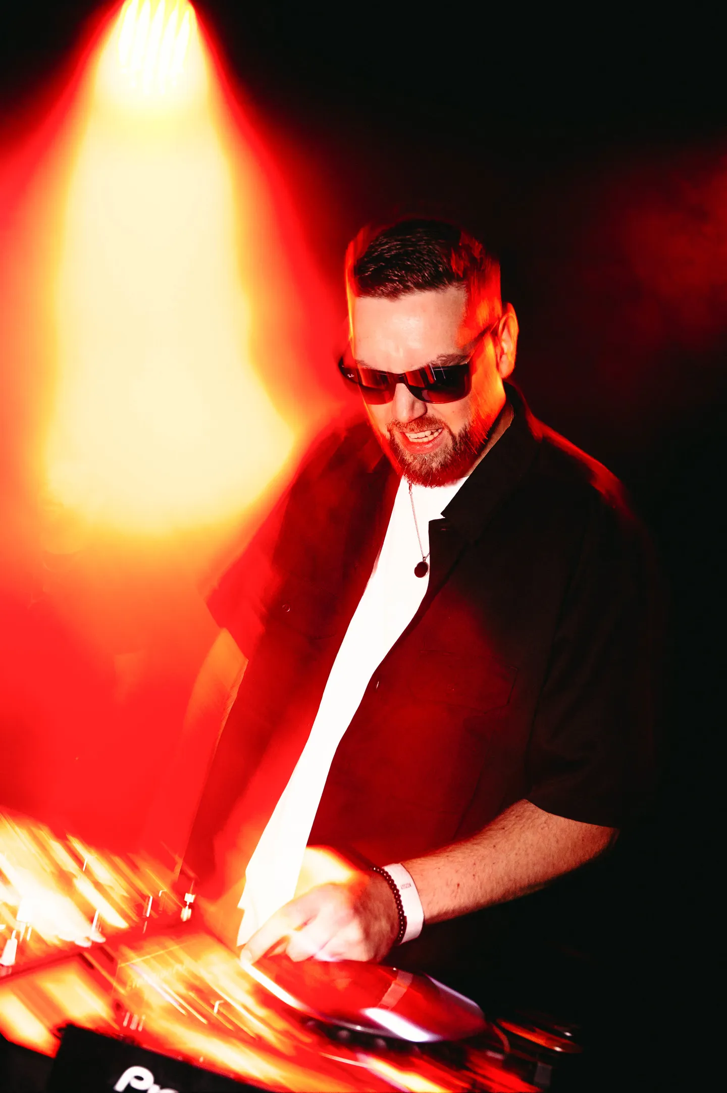DJ aux platines sous un éclairage rouge et orange
